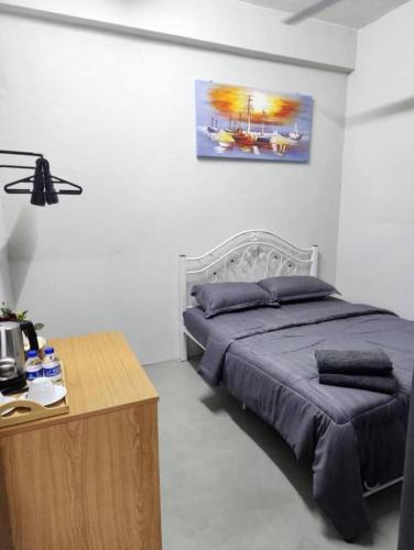 a bedroom with a bed and a wooden table at MDF Payang Guesthouse in Kuala Terengganu