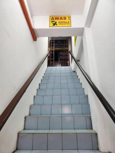 a staircase leading up to a building with a sign on it at MDF Payang Guesthouse in Kuala Terengganu
