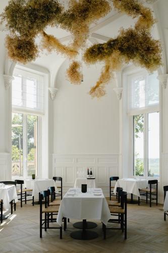 une salle à manger avec des tables et des chaises blanches et des fenêtres dans l'établissement Les Hauts de Sancerre, à Sancerre