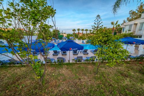 a group of blue umbrellas and chairs and a pool at Hotel Rais in El Marsa