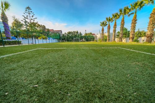 a soccer field in a park with palm trees at Hotel Rais in El Marsa