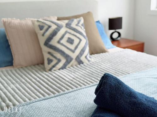 a bed with blue and white pillows on it at Cozy Stay 4BR Townhouse in Pimpama