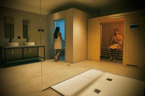 a woman standing in a bathroom with a man in a mirror at Acca Sporting Milano - AA Hotels in Opera