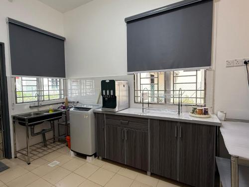 a kitchen with a counter and a sink and two windows at Chill Inn Homestay in Jerantut