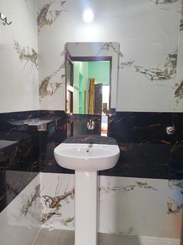 a bathroom with a white sink and a mirror at Ranjana Guesthouse in Hampi