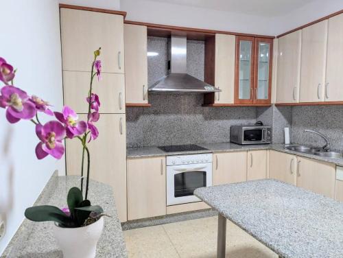 a kitchen with a table and a vase with purple flowers at Casa en el Camino de Santiago en Barro in Barro