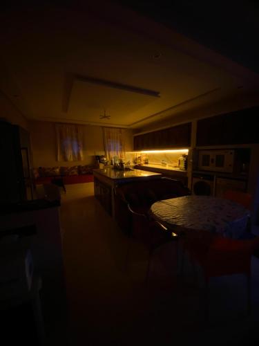 a dark living room with a table and a kitchen at villa cherif in Azib Oulad Lâdem