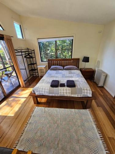 a bedroom with a bed and a large window at Bellingen - Hilltop Garden Studio in Bellingen