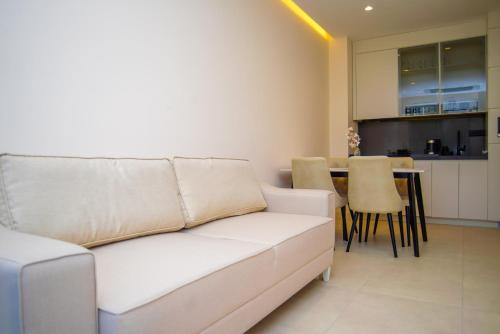 a living room with a white couch and a kitchen at Bellemond Hotel & Residences in Budva
