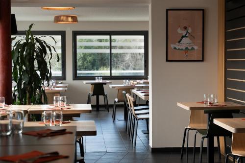 a dining room with tables and chairs and windows at Hôtel Restaurant Aldaburua in Larressore