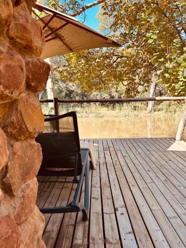 a rocking chair sitting on a wooden deck at Mologa River Lodge in Rust de Winter