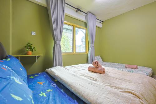 a teddy bear sitting on a bed in a bedroom at Modern Family Suite in Cameron Highlands Clover Home K2 in Cameron Highlands