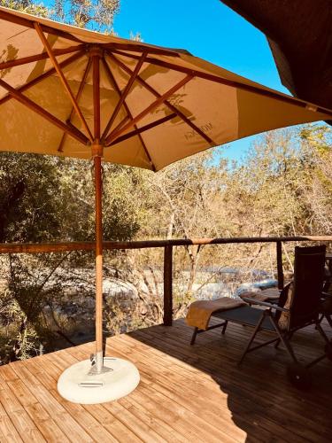 a yellow umbrella sitting on a deck with a chair at Mologa River Lodge in Rust de Winter
