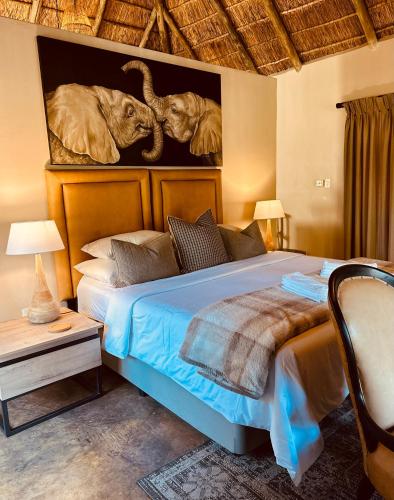 a bedroom with a bed with two elephants on the wall at Mologa River Lodge in Rust de Winter
