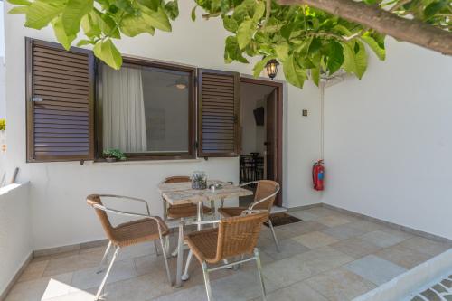 a patio with a table and chairs and a tree at SKYROS AVRA Residences in Skiros