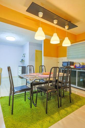 a dining room with a table and chairs on a green rug at Modern Family Suite in Cameron Highlands Clover Home K2 in Cameron Highlands