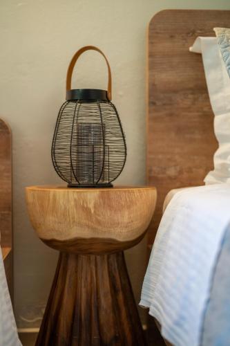 a lamp on a wooden table next to a bed at SKYROS AVRA Residences in Skiros
