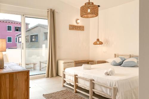a white bedroom with a bed and a balcony at Petra Maris Luxury Rooms in Santa Teresa Gallura
