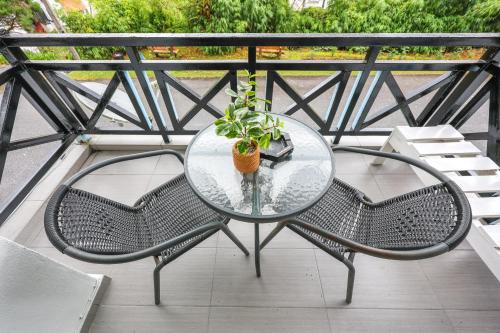 a glass table with two chairs and a potted plant at Modern Family Suite in Cameron Highlands Clover Home K2 in Cameron Highlands