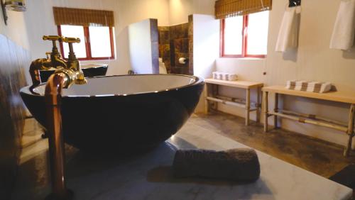 a bathroom with a black bath tub and a sink at Mologa River Lodge in Rust de Winter