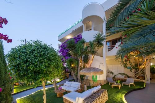 a building with a yard with furniture and trees at Apartamentos Estanques in Colònia de Sant Jordi