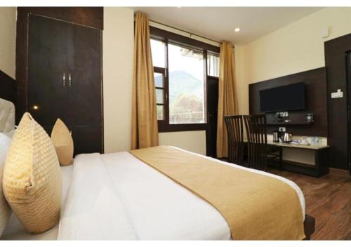 a bedroom with a bed and a window and a table at Hotel Mirage Residency in Dharmsala