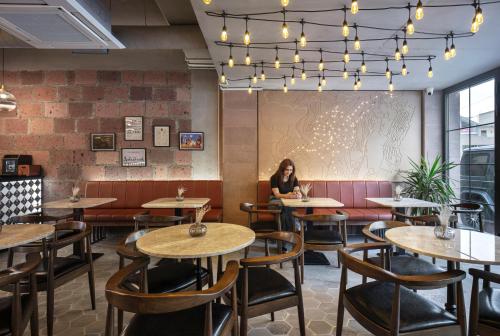 a woman sitting at a table in a restaurant at AREA Hotel Yerevan in Yerevan