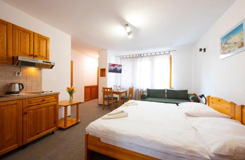 a bedroom with a large white bed and a kitchen at Penzion Snezienka in Tatranská Lomnica
