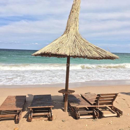 two lounge chairs and an umbrella on a beach at Blue Feelings Studio in Mamaia Nord