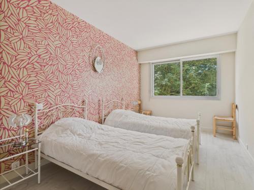 une chambre avec deux lits et un mur rouge dans l'établissement Appartement pour 4 au coeur de La Baule, à La Baule