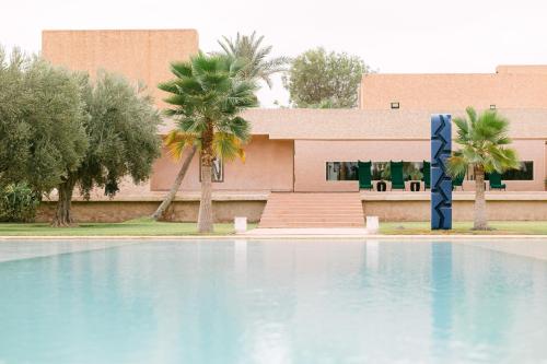 a swimming pool in front of a building with palm trees at Dar Sabra in Marrakech