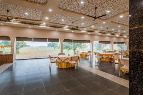 a dining room with tables and chairs and windows at Hotel Highway King Neemrana in Neemrana