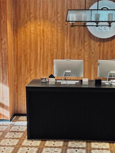 a black desk with two computers on a wooden wall at Yuanjili International Youth Hostel in Qingdao