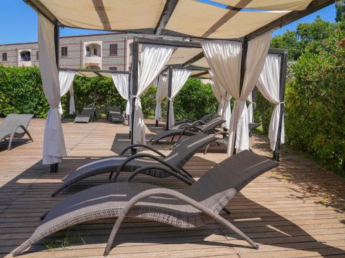 a row of chaise lounges on a patio at Hotel La Caletta Village in La Caletta