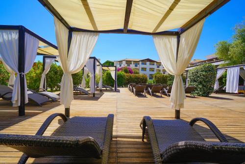 a deck with chairs and umbrellas at Hotel La Caletta Village in La Caletta