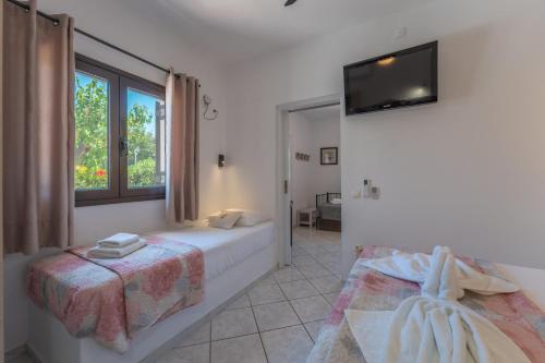 a bedroom with two beds and a television on the wall at SKYROS AVRA Residences in Skiros