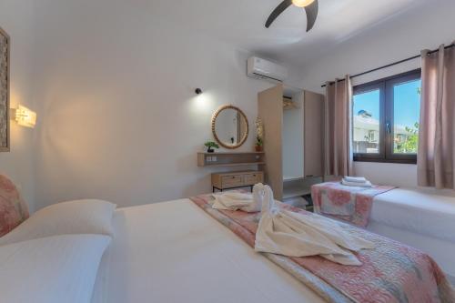 a bedroom with two beds and a mirror and a window at SKYROS AVRA Residences in Skiros