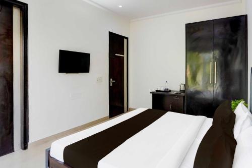 a bedroom with a bed and a tv on the wall at Collection O Sector 53 Golf Course Road in Gurgaon