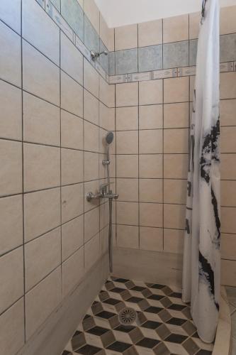 a bathroom with a shower with black and white tiles at SKYROS AVRA Residences in Skiros