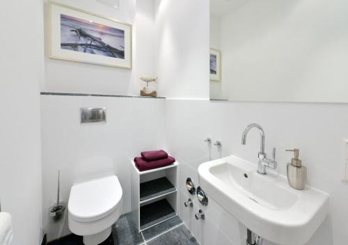 ein weißes Badezimmer mit Toilette und Waschbecken in der Unterkunft Ferienwohnung Silbermöwe in Sassnitz