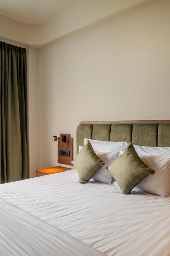 a bedroom with a bed with white sheets and pillows at Hotel Highway King Neemrana in Neemrana