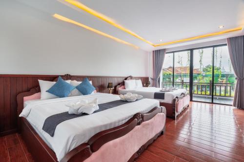 a hotel room with two beds and a large window at Pich Kunthea Angkor Resort in Phumĭ Kruŏs