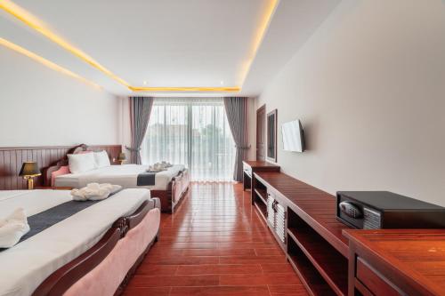 a hotel room with two beds and a television at Pich Kunthea Angkor Resort in Phumĭ Kruŏs