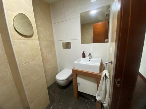 a bathroom with a sink and a toilet and a mirror at Apartamento céntrico al lado de la playa in Bueu