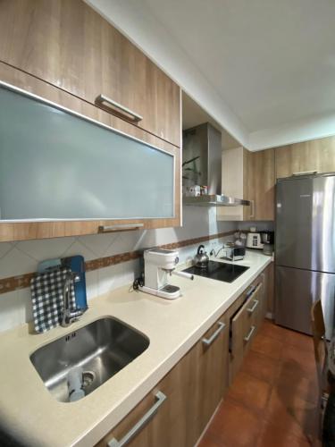 a kitchen with a sink and a stainless steel refrigerator at Apartamento céntrico al lado de la playa in Bueu
