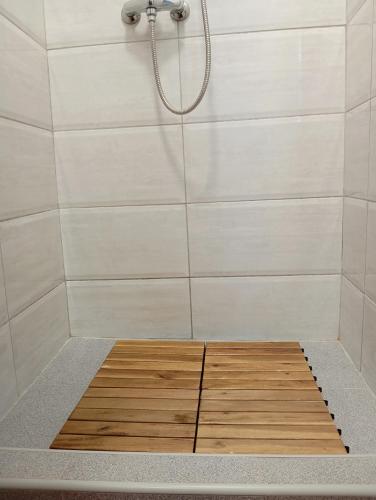 a shower with a wooden floor in a bathroom at Apartment Natti in Sremska Kamenica