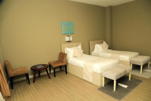 a room with two beds and a table and chairs at Haile Resort Jimma in Jīma