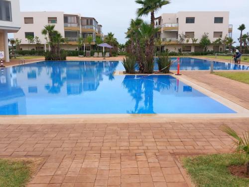 a large blue swimming pool in front of a building at Résidence blue beach Sidi rahal in Sidi Rahal