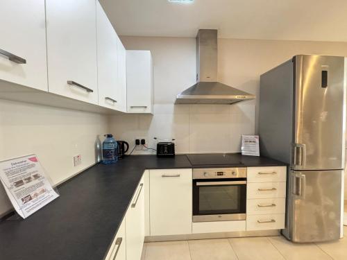 a kitchen with white cabinets and a stainless steel refrigerator at Sea Breeze Terrace - Marsaskala in Taʼ Monita
