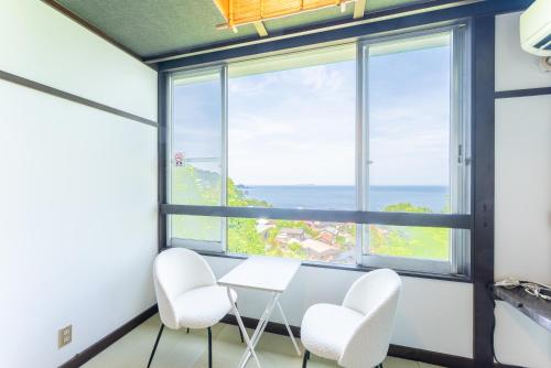 a room with a table and chairs and a large window at Villa FUN Kawana in Ito